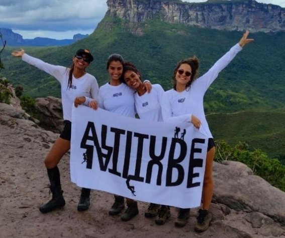 A group of smiling hikers with backpacks standing in front of a waterfall.